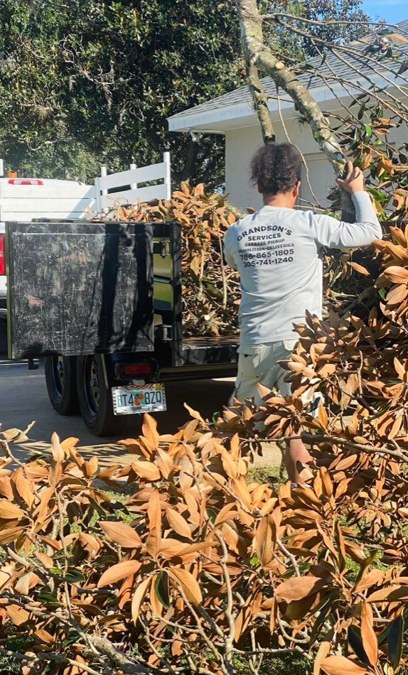 Crew member loading tree branches into a Grandson's Services trailer